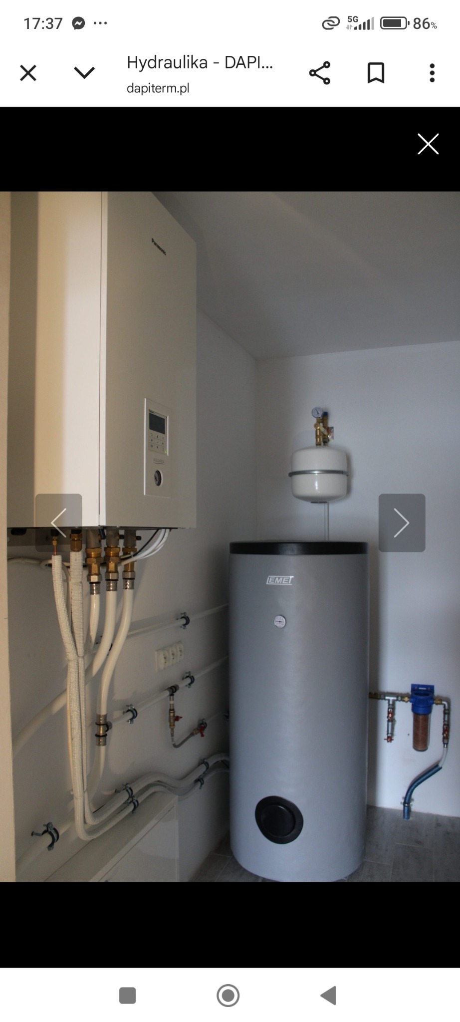 Biały piec gazowy Panasonic i szary zasobnik ciepłej wody Emet w schludnej kotłowni z białymi ścianami i widoczną instalacją hydrauliczną.