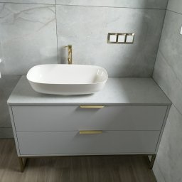 HEXA SC - Nowoczesna szafka łazienkowa z umywalką nablatową, złota armatura i uchwyty, marmurowe płytki w tle. Minimalistyczny design.