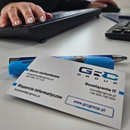 GRC Group sp. z o.o. - Biuro rachunkowe GRC Group: wizytówka na biurku obok klawiatury i długopisu. Oferta wsparcia informatycznego i rozwiązań IT. Kontakt: ksiegowosc@grcgroup.pl.