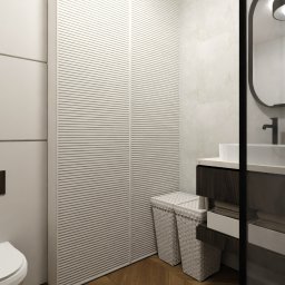 PRACOWNIA ARCHITEKTONICZNA DYALA ARRABI - Nowoczesna łazienka z toaletą, umywalką na szafce z ciemnego drewna, lustrem w czarnej ramie i szafą z lamelami. Dwie białe, plecione skrzynie na podłodze z parkietu.