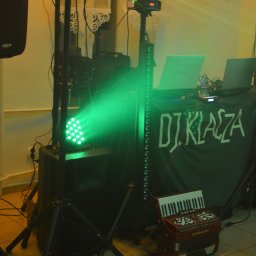 DJ KLACZA-Wodzirej z akordeonem - Scena DJ'a z zielonym oświetleniem, nagłośnieniem i akordeonem. Na stole laptopy i mikser. Na froncie napis 'DJ KLAZA'.