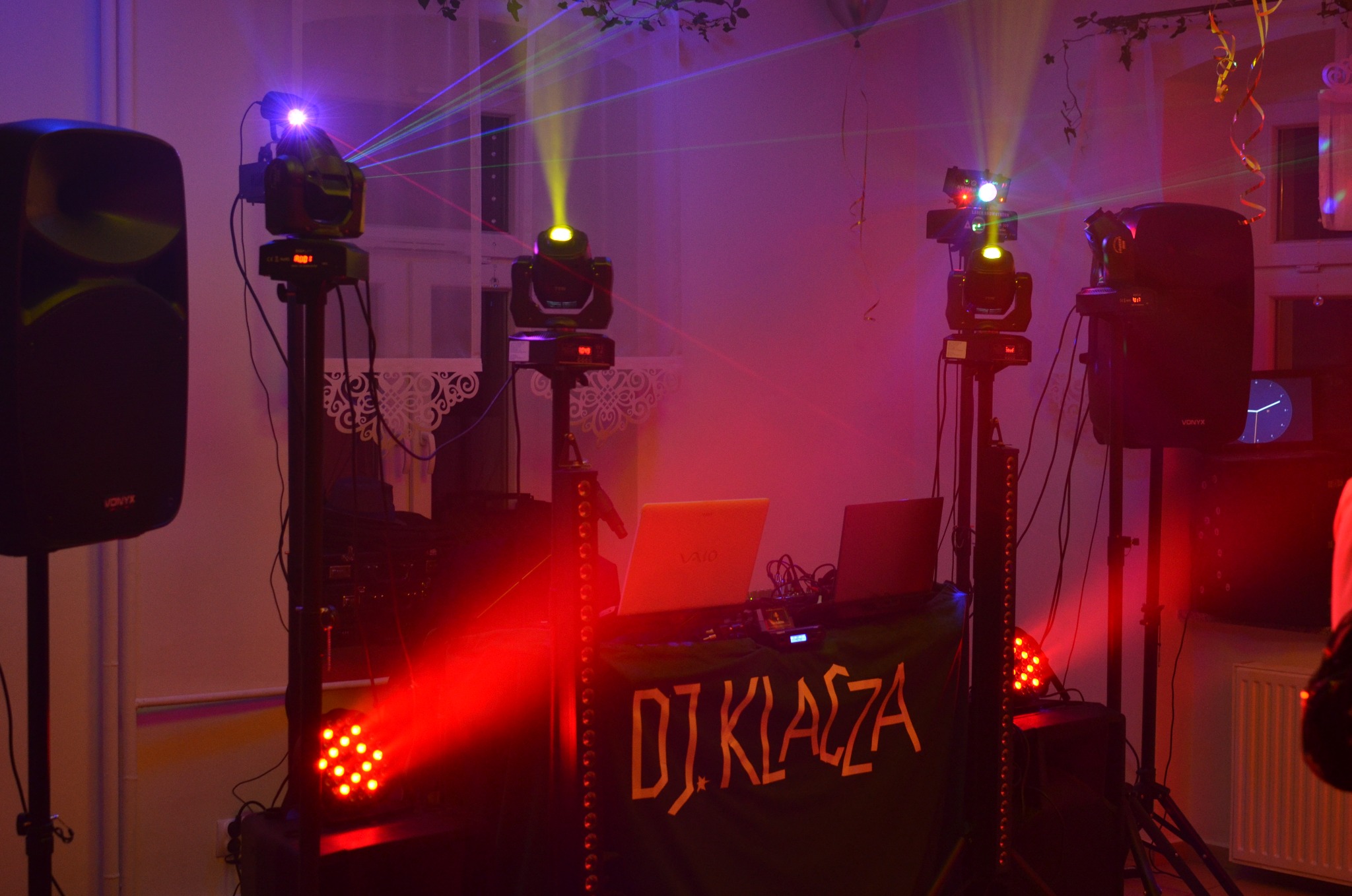 Scena DJ-a z nagłośnieniem i oświetleniem: reflektory, lasery, kolumny głośnikowe Vonyx i baner z napisem 'DJ KLACZA' w czerwono-fioletowej poświacie.