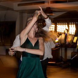 M&M EVENTS MAREK MURAWSKI - Rozmazane ujęcie tańczących osób na parkiecie, z widocznym oświetleniem eventowym w tle, tworzące dynamiczną atmosferę imprezy.