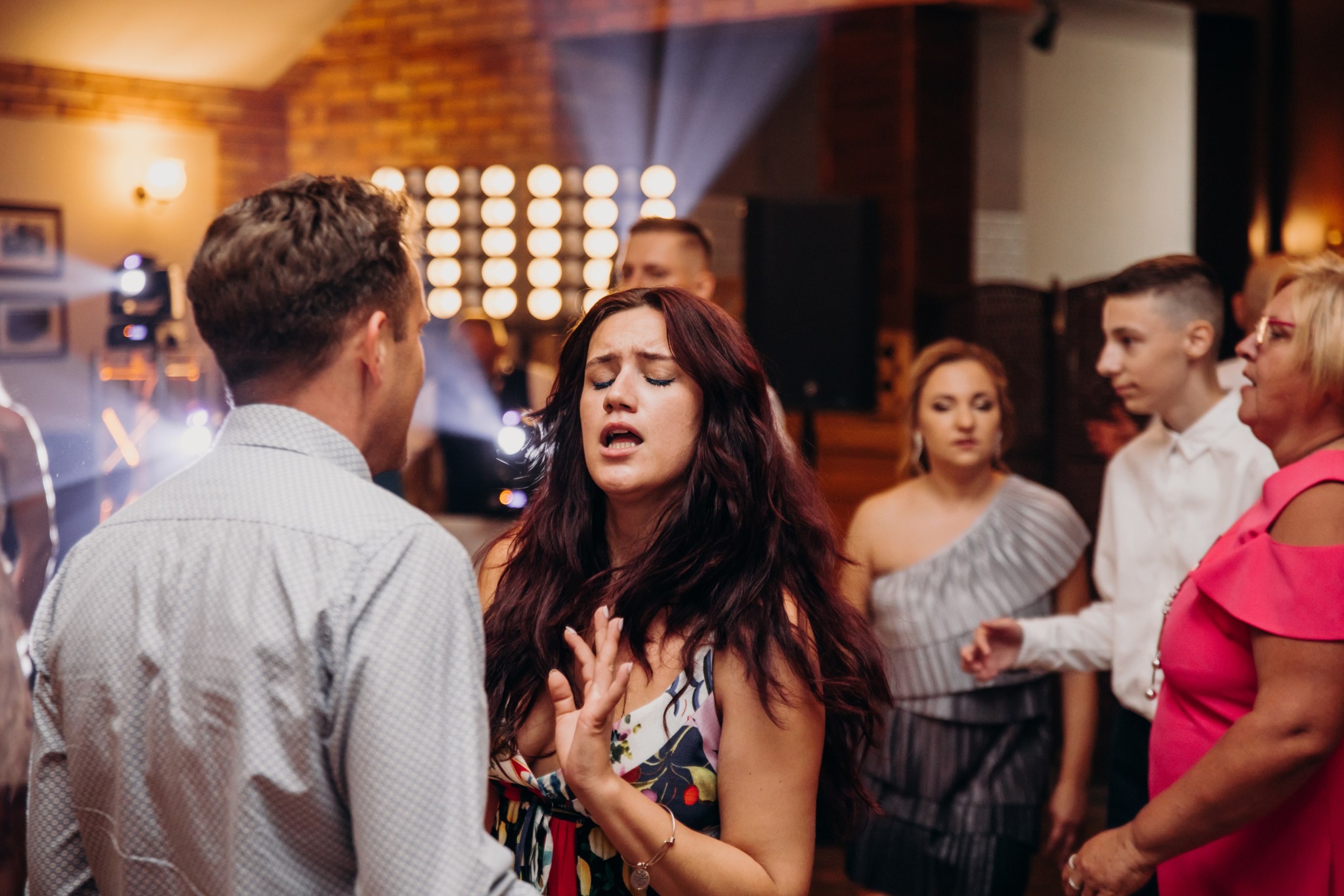 Wokalistka z ekspresją śpiewa podczas występu w Łapach, otoczona publicznością. W tle widoczne oświetlenie sceniczne, tworzące intymną atmosferę wydarzenia.