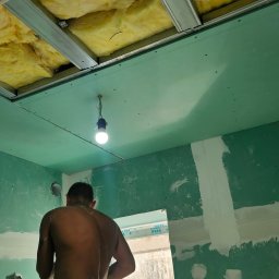 VAN GLOBAL SPÓŁKA Z OGRANICZONĄ ODPOWIEDZIALNOŚCIĄ - Montaż sufitu podwieszanego z płyt gipsowo-kartonowych i ociepleniem wełną mineralną. Widoczny pracownik podczas szpachlowania łączeń płyt.