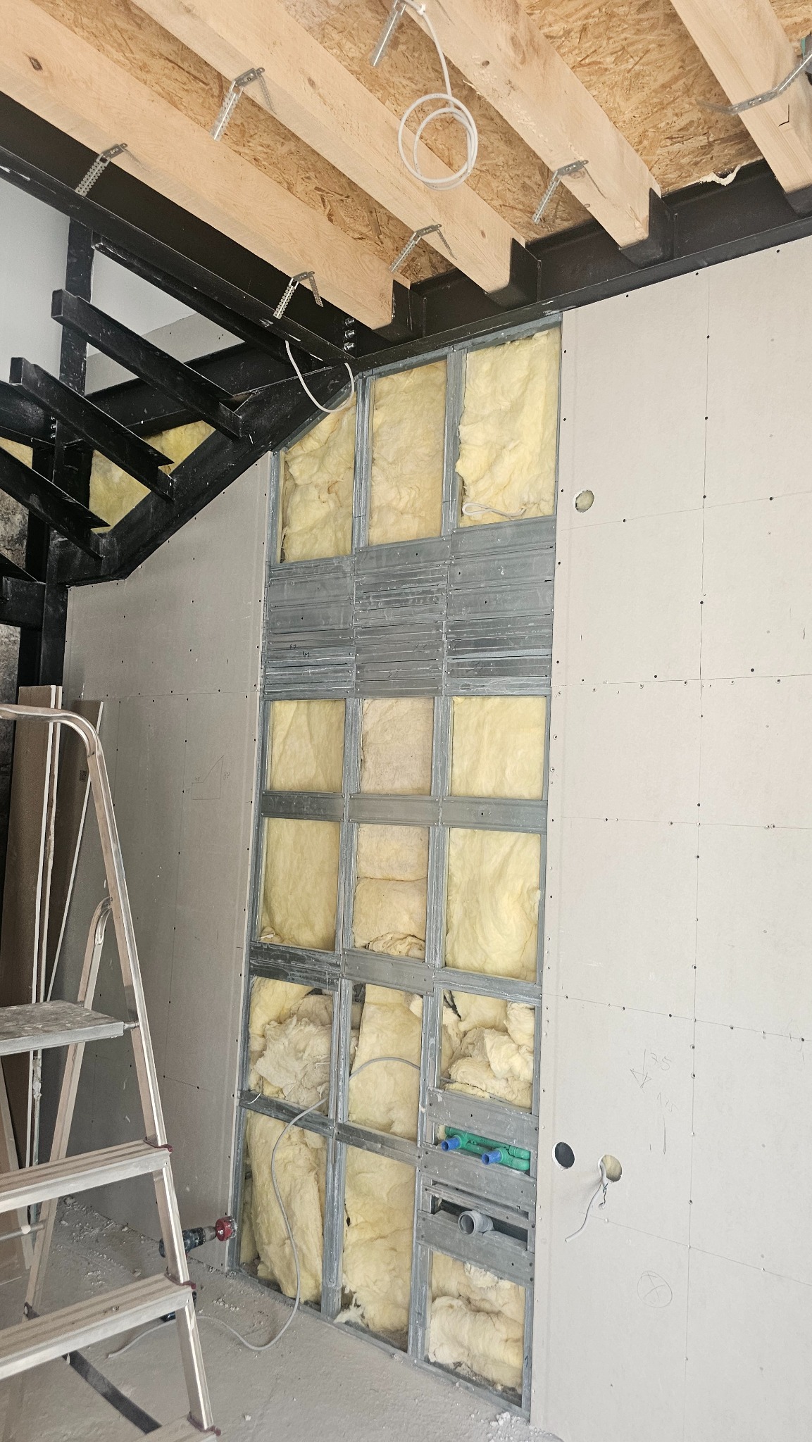 Ściana z izolacją z wełny mineralnej i płytami gipsowo-kartonowymi w trakcie remontu w Katowicach. Widoczne elementy konstrukcyjne i instalacje.