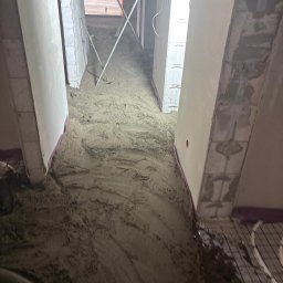 Posadzki Maszynowe - Posadzki Przemysłowe - ZAMBUD - Wnętrze w trakcie wylewki posadzki maszynowej z widocznym ogrzewaniem podłogowym i narzędziami. Ściany surowe, przygotowane do dalszych prac wykończeniowych.