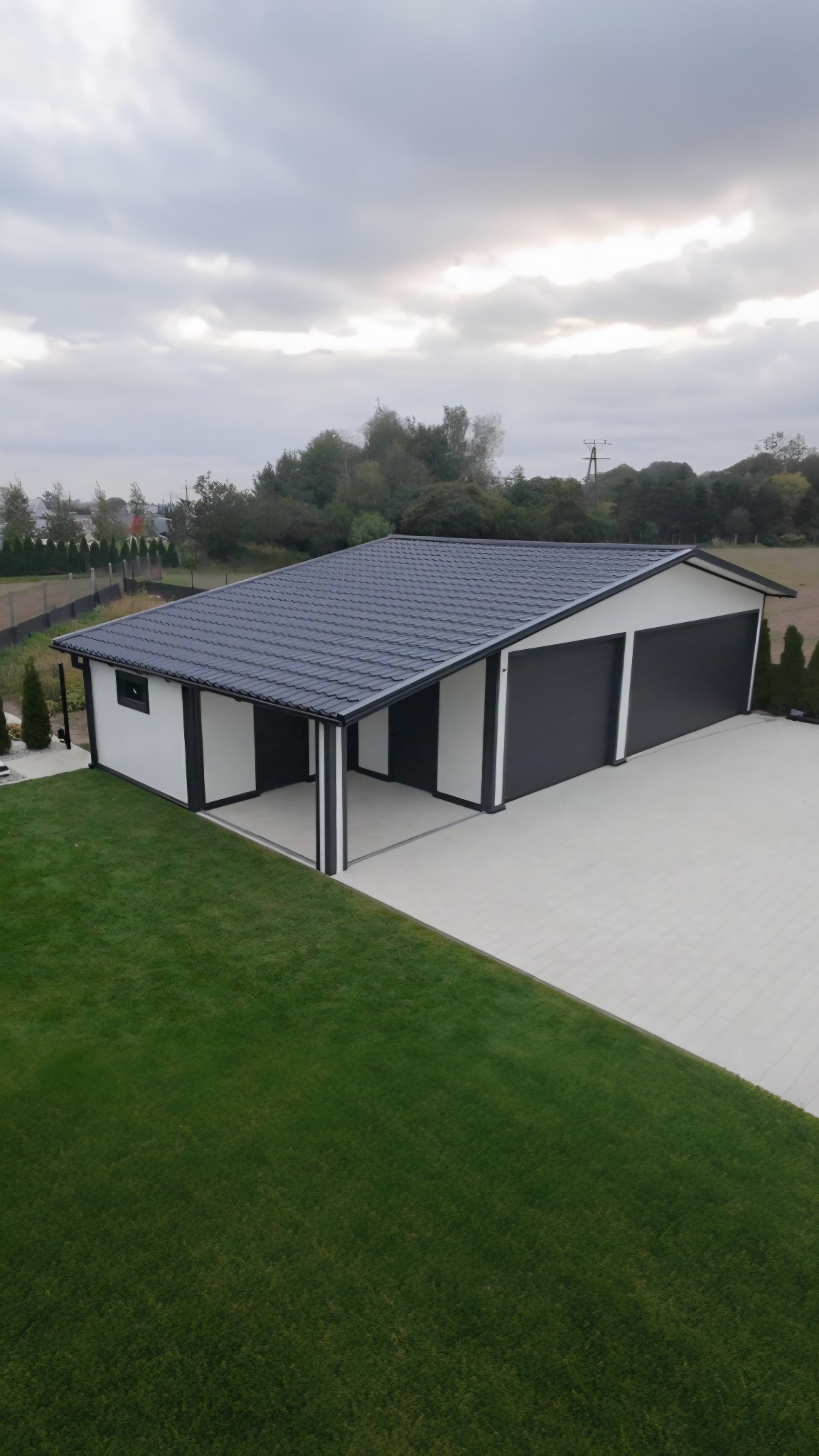 Nowoczesny garaż dwustanowiskowy z płyty warstwowej w kolorze białym i antracytowym w Słupi. Widok z góry ukazuje estetyczne wykończenie i zagospodarowanie terenu.