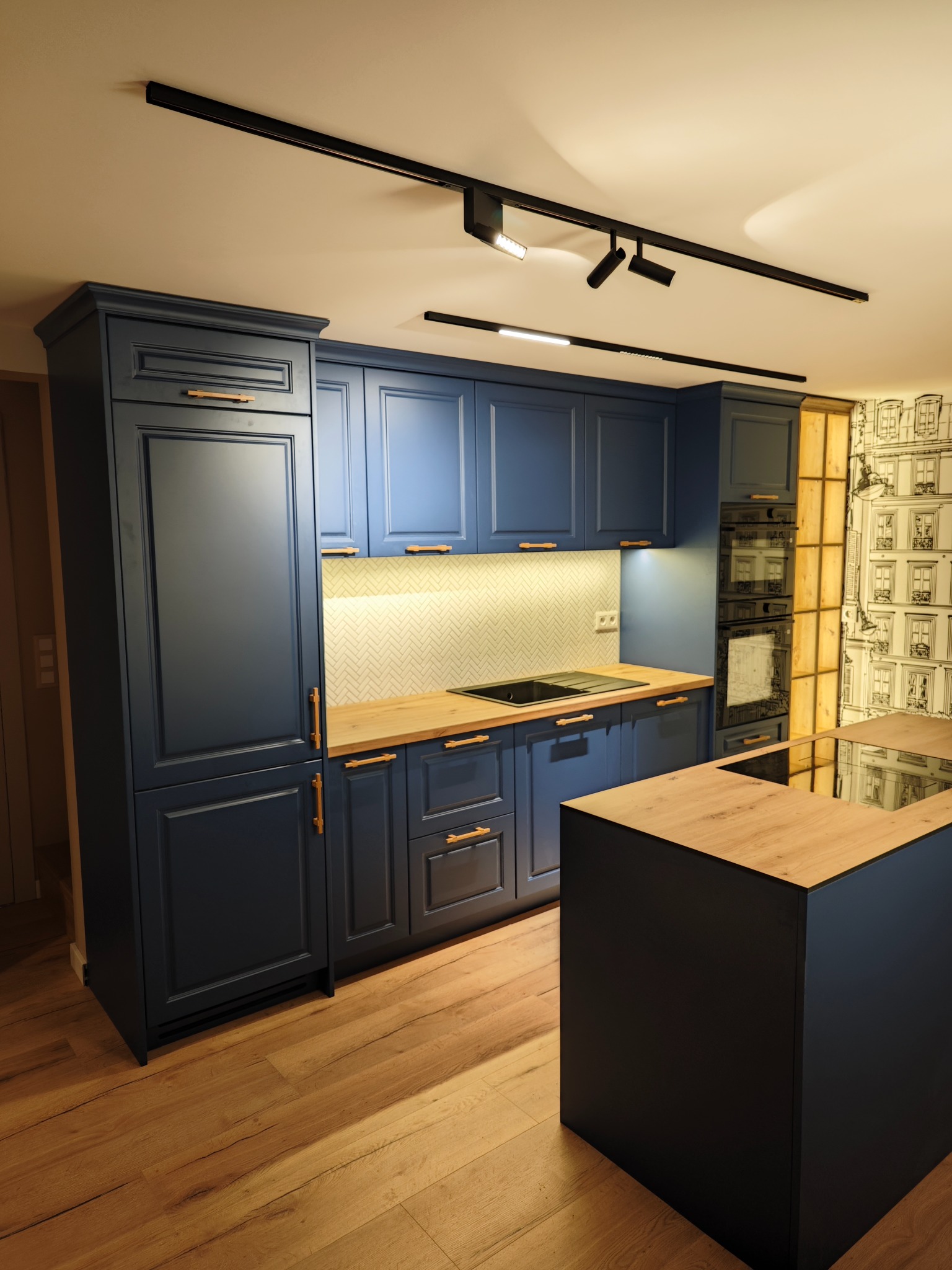 Granatowa zabudowa kuchenna z drewnianymi blatami i wyspą, oświetlenie punktowe, parkiet. Klasyczny styl z nowoczesnymi akcentami.
