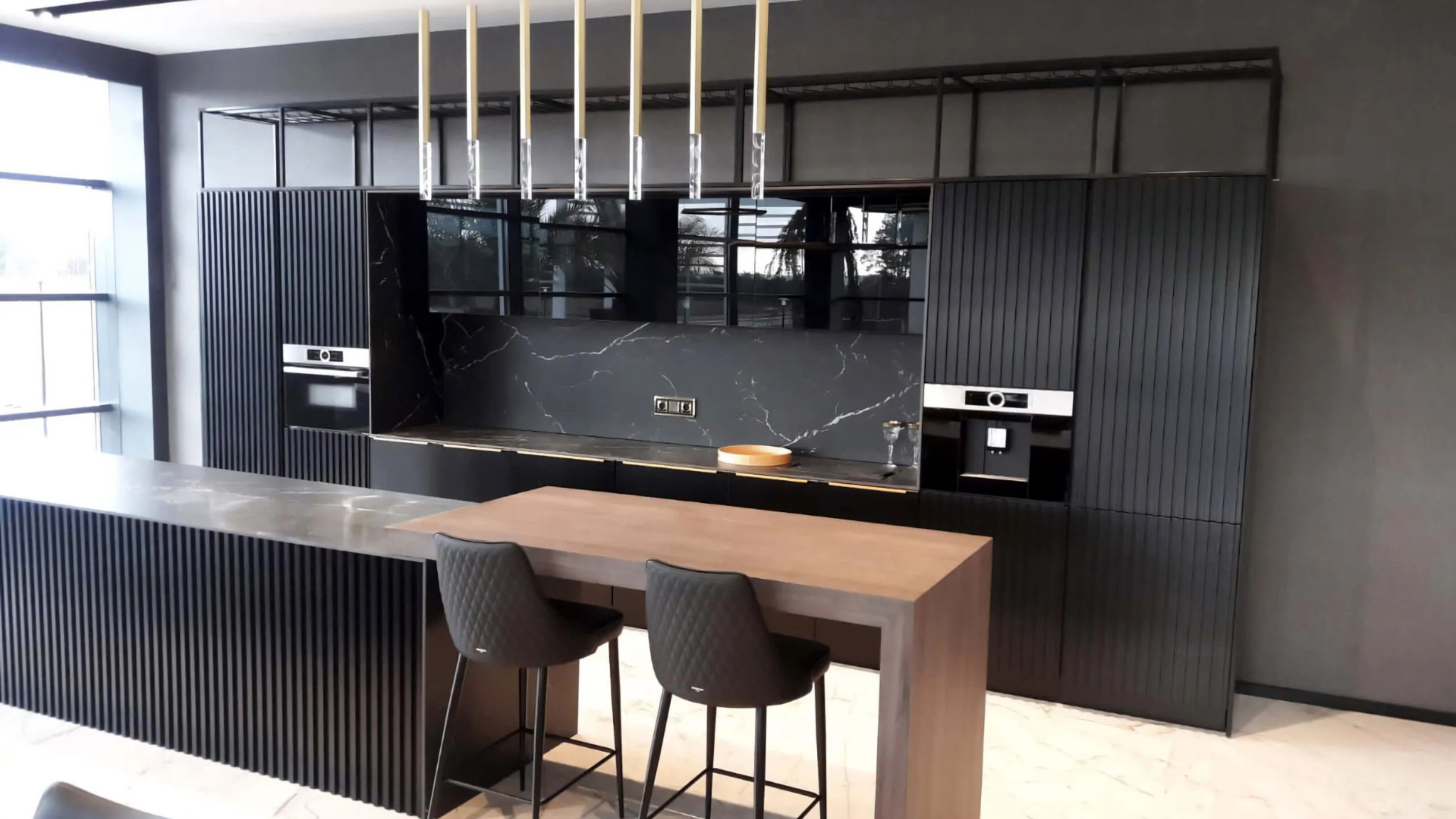 Nowoczesna, czarna kuchnia na wymiar we Wrocławiu z wyspą i marmurowym blatem. Minimalistyczny design, oświetlenie punktowe, eleganckie krzesła barowe.