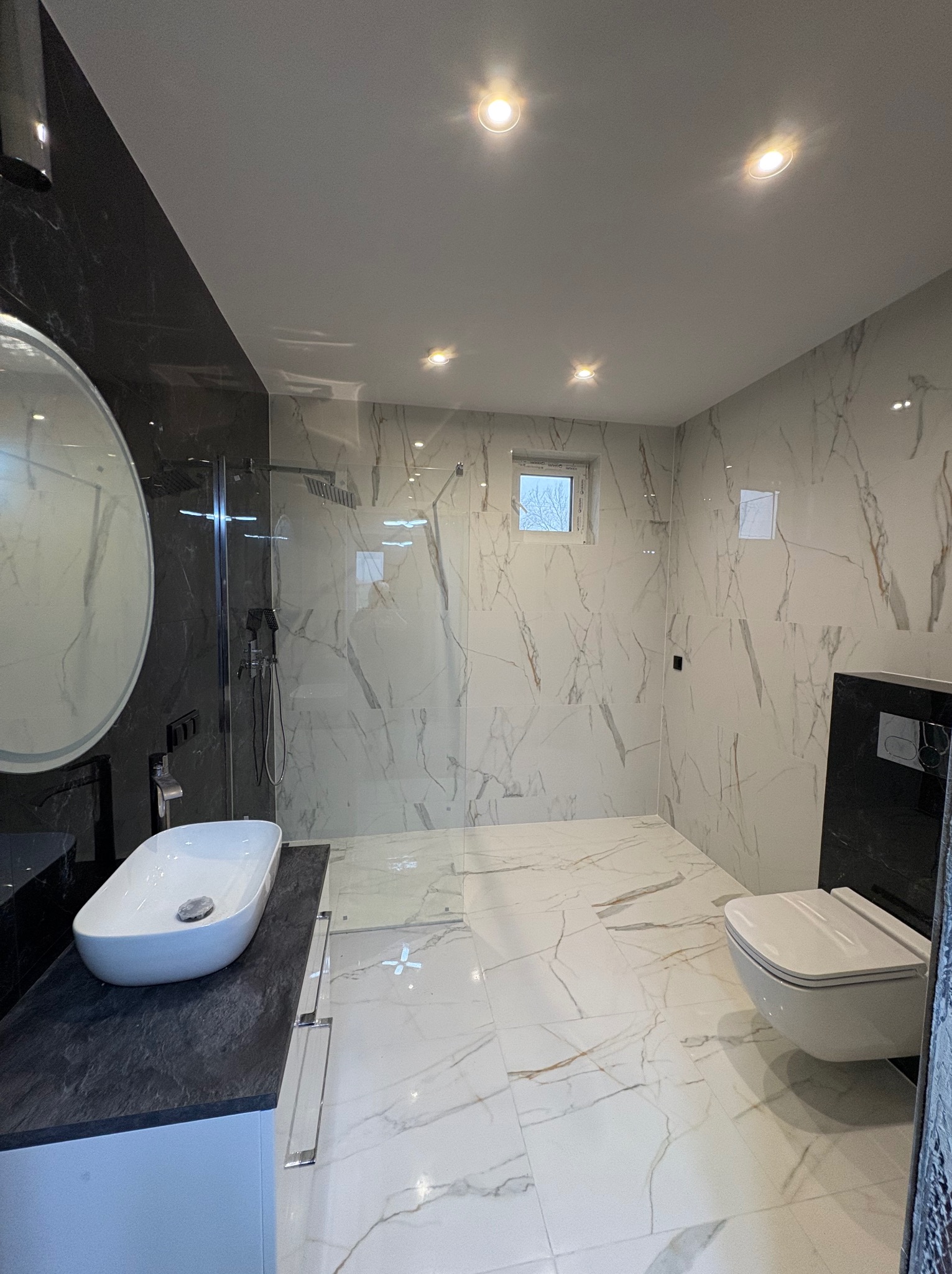Elegancka łazienka w Łodzi z marmurowymi płytkami, kabiną prysznicową typu walk-in i owalną umywalką nablatową. Nowoczesne oświetlenie punktowe.