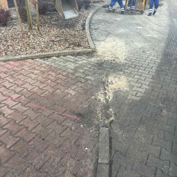 GryCars Michał Grykałowski - Prace brukarskie w toku: ekipa robotników wyrównuje teren pod kostkę brukową. Widoczny fragment ułożonej kostki, piasek i maszyny budowlane. Ujęcie z góry.