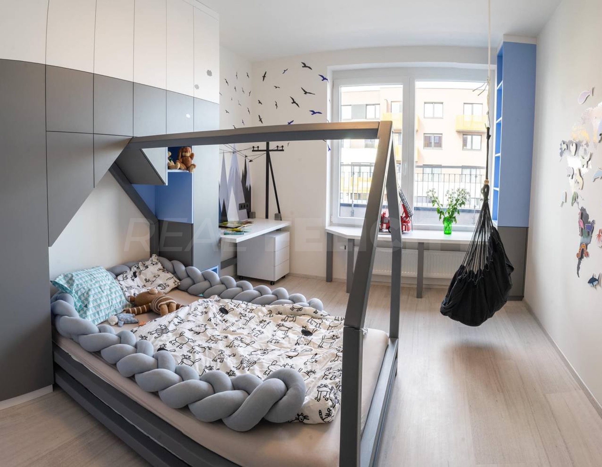 Nowoczesny pokój dziecięcy z łóżkiem w kształcie domku, biurkiem i wiszącym fotelem. Jasne kolory, minimalistyczny design, zabawne dekoracje na ścianach.