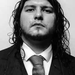 Jakub Groborz - Czarno-biały portret mężczyzny w garniturze, z mokrymi włosami i kroplami wody na ubraniu, patrzącego prosto w obiektyw, w studio.