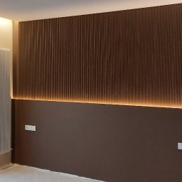 Oleh Mytulynskyi - Nowoczesna ściana z brązowymi panelami i subtelnym podświetleniem LED, grzejnik, okno balkonowe. Minimalistyczny design wnętrza.