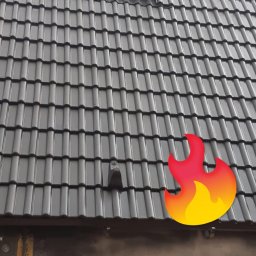 Specjaliści od Renowacji,Wysokości i Wycinek 66-400 - Ciemnoszary dach z ceramicznych dachówek, z zamontowanym, zabezpieczonym folią oknem dachowym i elementem wentylacyjnym, widoczna krawędź dachu z ociepleniem.