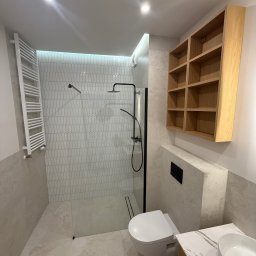 Globi-Bud - Nowoczesna łazienka po remoncie: kabina walk-in z czarną armaturą, białe płytki w kształcie łezki, drewniana szafka i umywalka nablatowa. Minimalistyczny design.