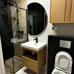 Mykyta Sichkar S-KAR BUD - Nowoczesna łazienka z kabiną prysznicową typu walk-in, okrągłym lustrem i wiszącą szafką z umywalką. Uwagę zwraca czarna ściana z białymi żyłami.