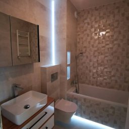 DS Wykończenia Dariusz Szczygłowski - Nowoczesna łazienka z podświetleniem LED: umywalka nablatowa, geometryczne płytki 3D, zabudowana toaleta. Minimalistyczny design z akcentami światła.
