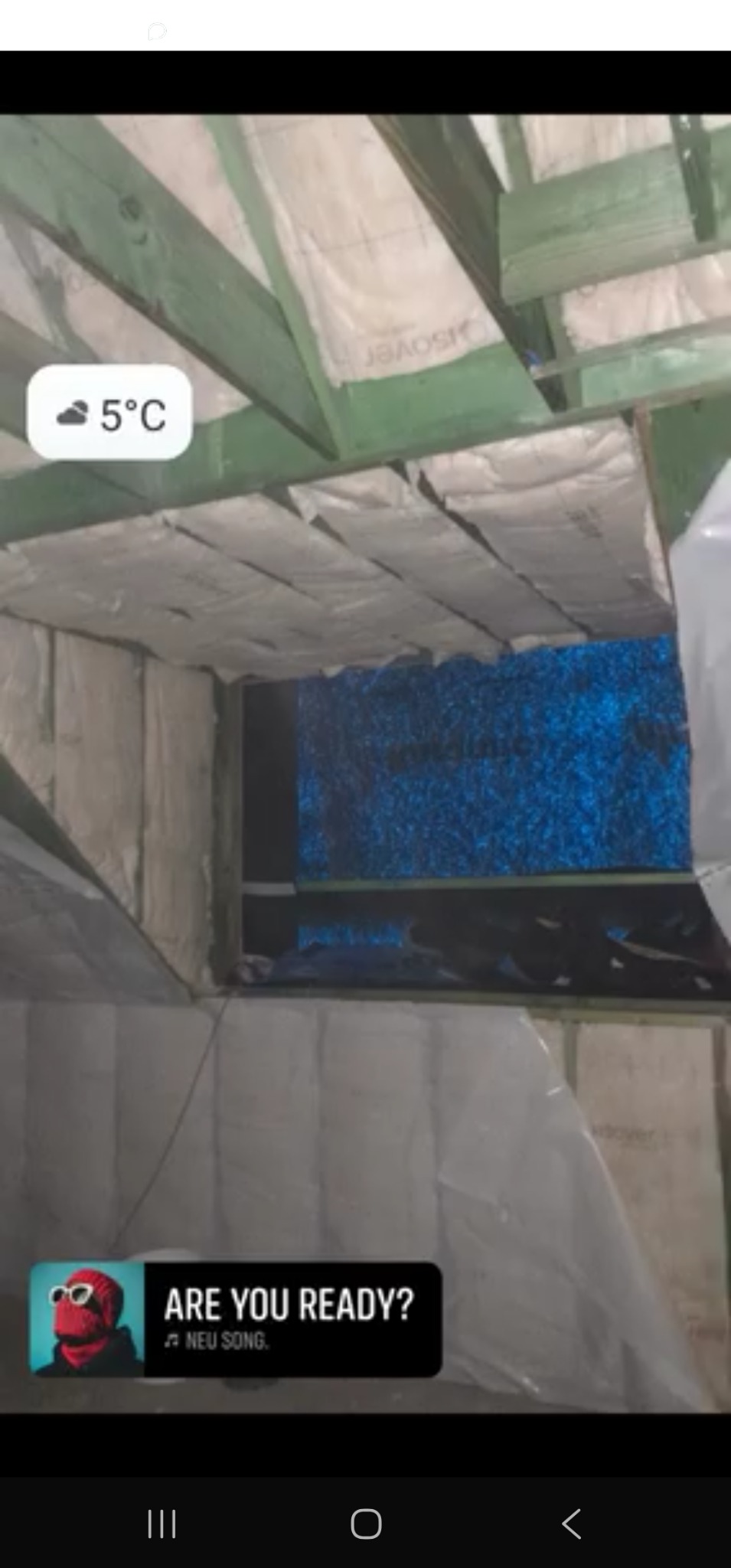 Poddasze z widoczną izolacją termiczną między krokwiami. Biała wełna mineralna szczelnie wypełnia przestrzeń. Widoczne drewniane elementy konstrukcji dachu.