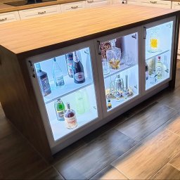 Podświetlana wyspa ,z jednej strony witryna ,z drugiej szuflady i miejsce na butelki ,fronty lakierowane ,frezowane 