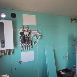 SYLGRE Instalacje Damian Janiszewski - Nowoczesna kotłownia w trakcie montażu w Kwidzynie. Widoczny piec gazowy, zbiornik, instalacja na płycie OSB. Elementy instalacji grzewczej.