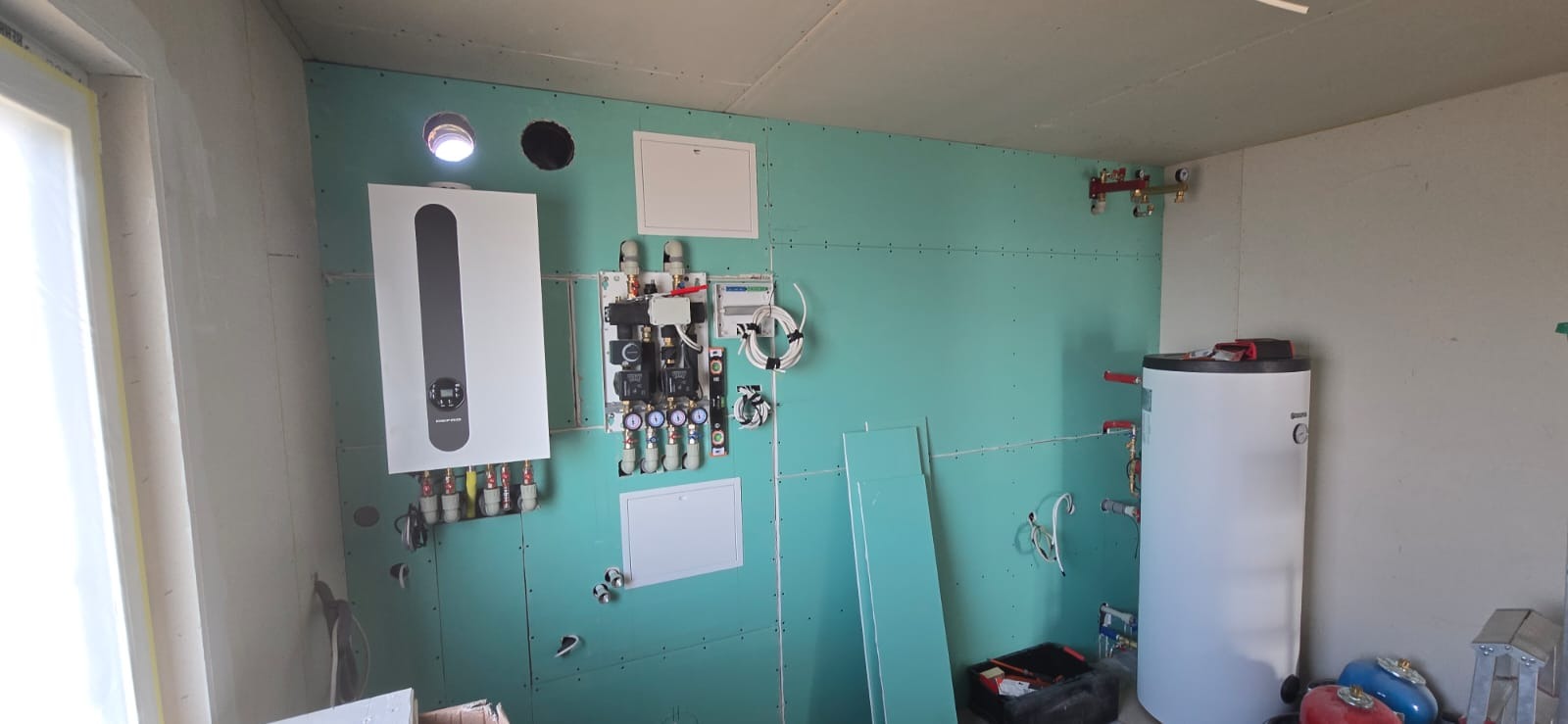 Nowoczesna kotłownia w trakcie montażu w Kwidzynie. Widoczny piec gazowy, zbiornik, instalacja na płycie OSB. Elementy instalacji grzewczej.