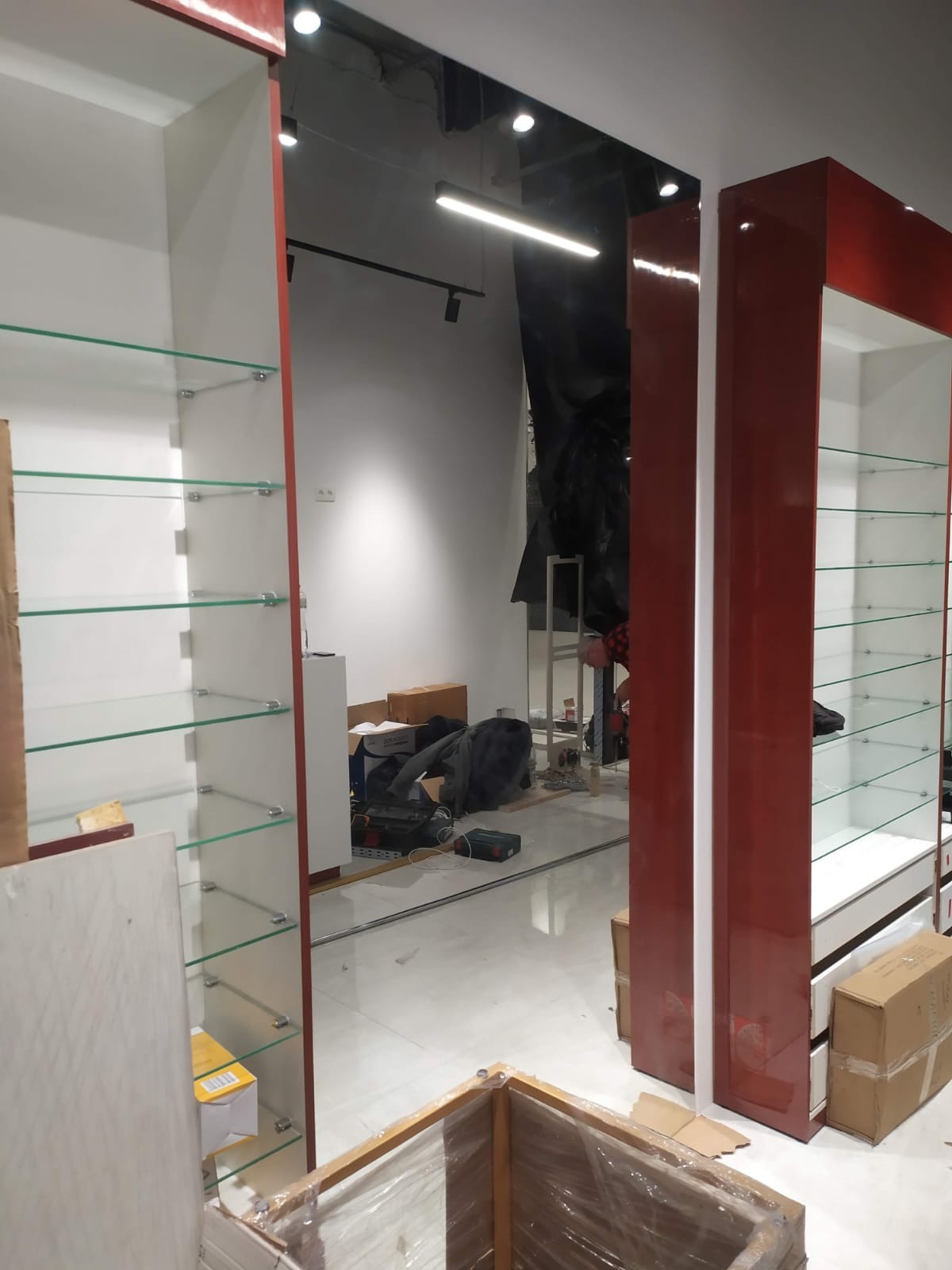 Montaż witryn sklepowych z półkami szklanymi w Mysłowicach. Widoczne elementy konstrukcyjne i narzędzia, etap prac wykończeniowych w lokalu.