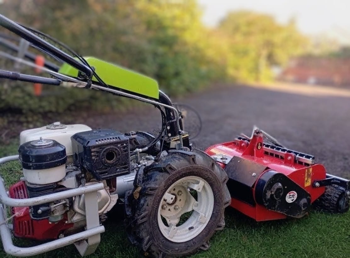 Glebogryzarka separacyjna, z bliska, na trawie w Rybniku. Czerwony agregat roboczy, białe felgi, zielony element. Sprzęt do przygotowania podłoża pod trawnik.