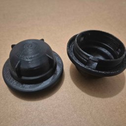 Mateusz Wujak - Czarne, rozdzielone elementy z tworzywa sztucznego, wydrukowane w technologii 3D, leżące na beżowym tle. Widoczne warstwy druku i detale konstrukcyjne.