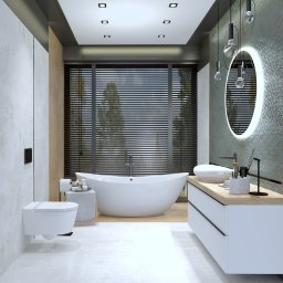 LeoArt - Nowoczesna łazienka z wolnostojącą wanną na tle okna z żaluzjami. Umywalka nablatowa, okrągłe lustro z podświetleniem LED i minimalistyczna toaleta.