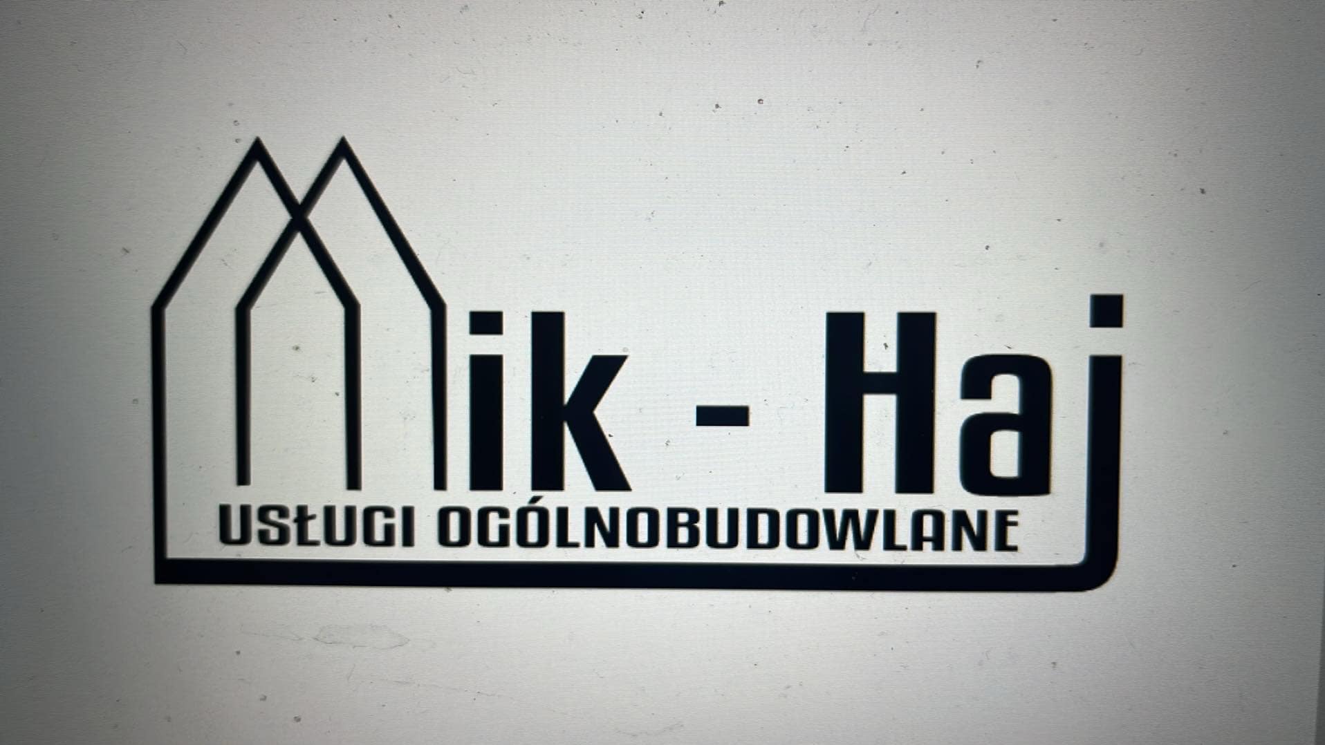 Logo firmy 'Mik-Haj' oferującej usługi ogólnobudowlane, z graficznym symbolem domu i nazwą firmy w czarnej, pogrubionej czcionce na jasnym tle.