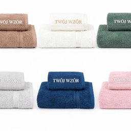 Aleksandra Hinc - Zestaw sześciu kompletów ręczników w różnych kolorach z wyhaftowanym napisem 'Twój Wzór', ułożonych na białym tle, prezentacja haftu na tekstyliach.