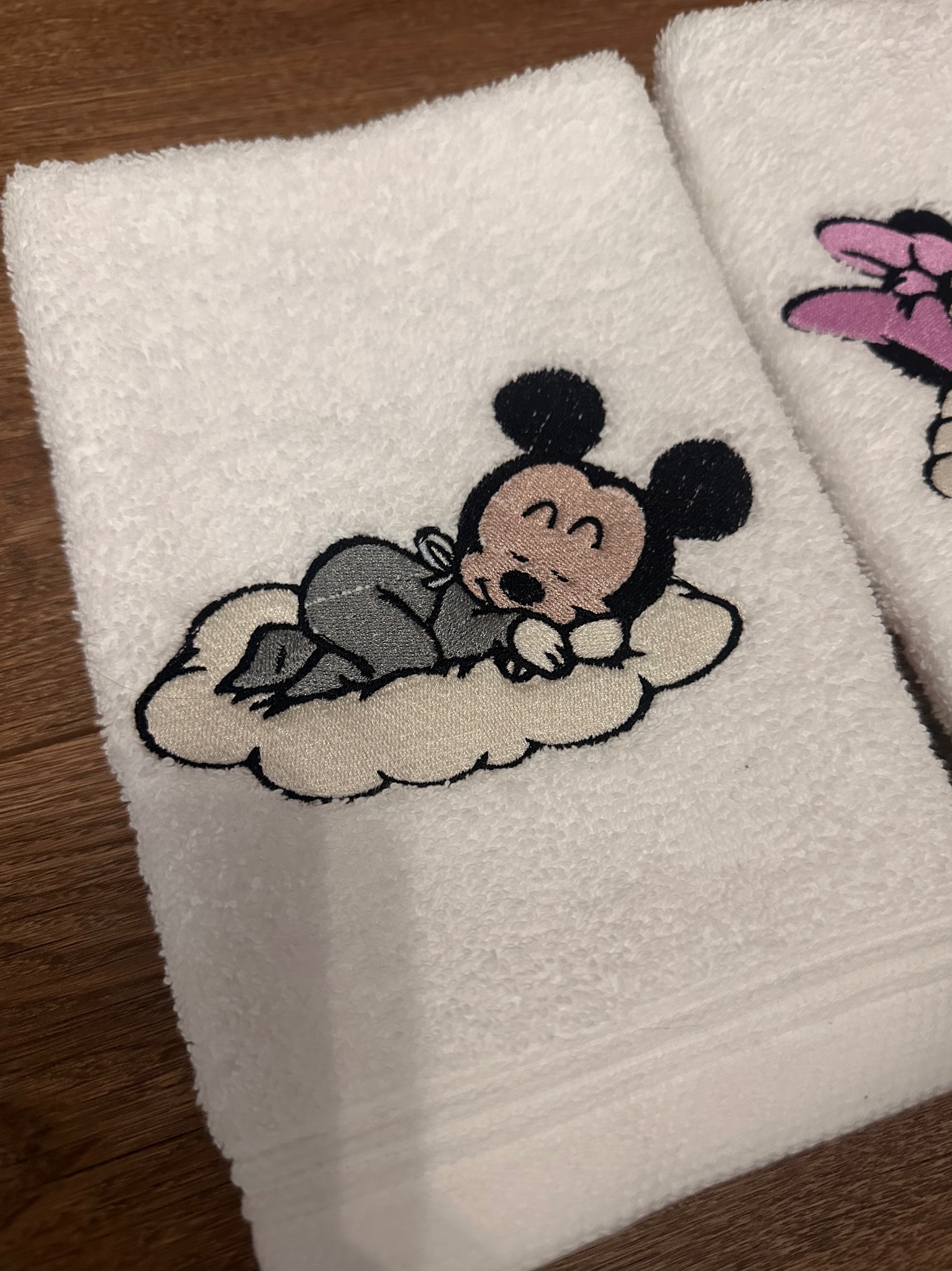 Biały ręcznik z haftem śpiącego Myszki Miki na obłoku, wykonany w Maszewie Lęborskim. Detal haftu z bliska, widoczna faktura materiału i precyzja wykonania.