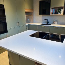 Adrian Hofman - Zabudowa kuchenna 7,6m. Fronty malowane; kolor oliwka, blat piaskowiec.