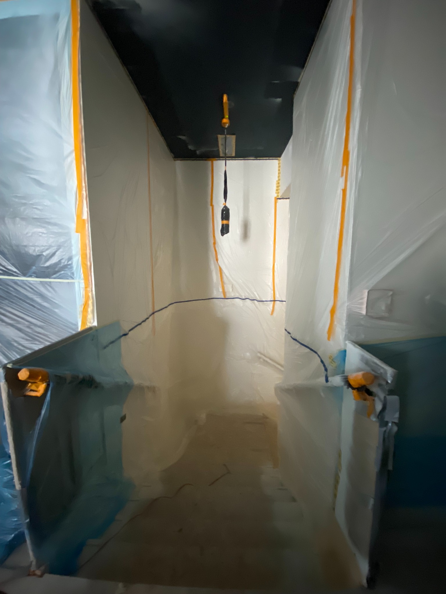 Przygotowanie do prac malarskich we Wrocławiu: pomieszczenie zabezpieczone folią i taśmą malarską, gotowe do malowania ścian i sufitu. Ochrona przed zabrudzeniami.