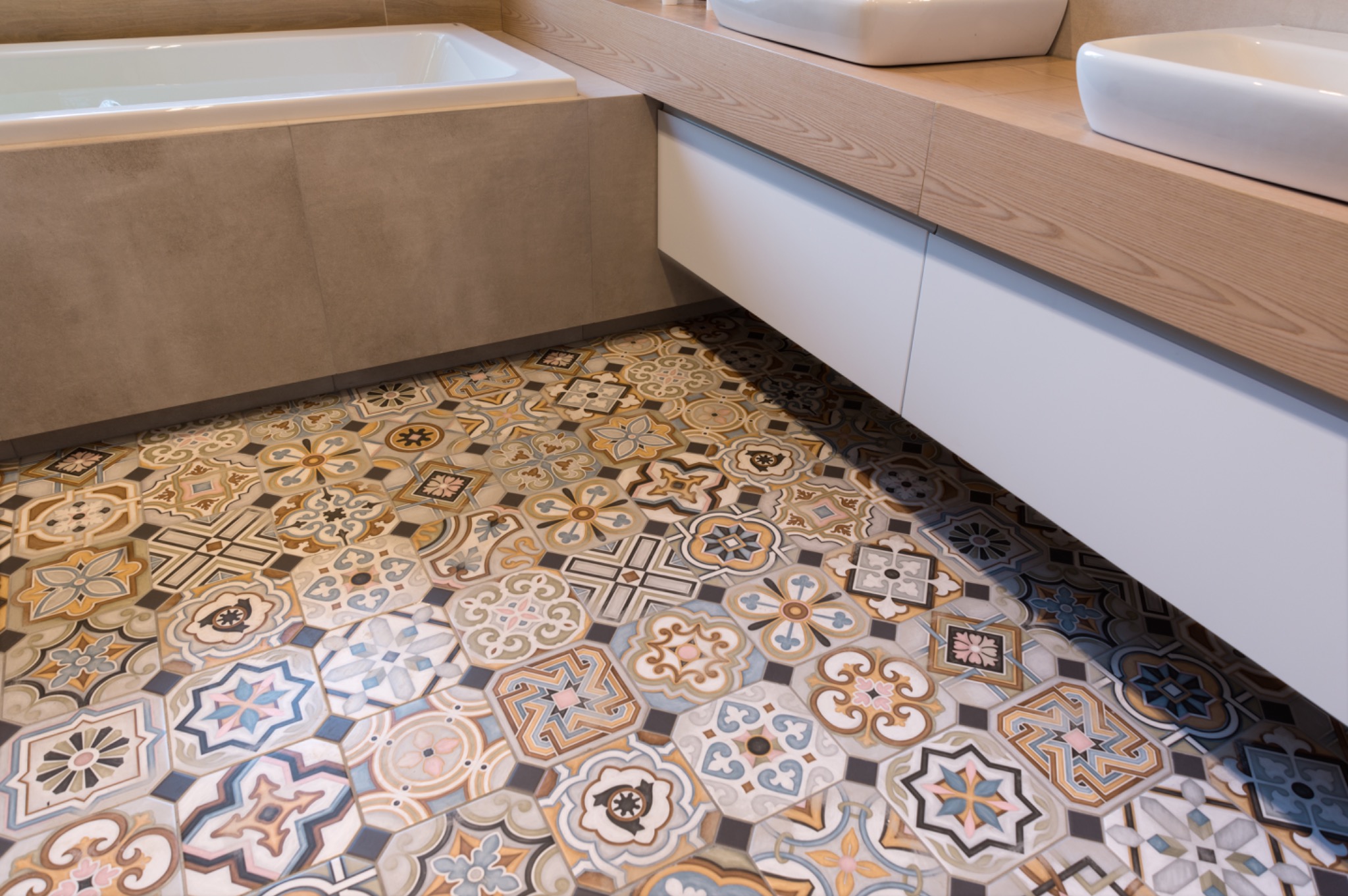 Wzorzysta, heksagonalna podłoga w łazience w Gliwicach. Ułożone płytki w stylu patchwork, z motywami kwiatowymi i geometrycznymi. Widoczna wanna i umywalka.