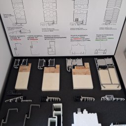 Justyna Pędziwiatr P&Home&Cars - Ekspozycja przekrojów okiennych i drzwiowych w czarnym kuferku: detale konstrukcyjne, materiały (drewno, PVC, aluminium), uszczelki. Prezentacja technologii i rozwiązań.