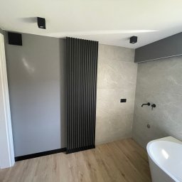 WOJCIECH BIERNACKI - Nowoczesna łazienka po remoncie: szare ściany, drewnopodobne panele, czarna dekoracyjna ścianka z listew, minimalistyczna armatura i oświetlenie.