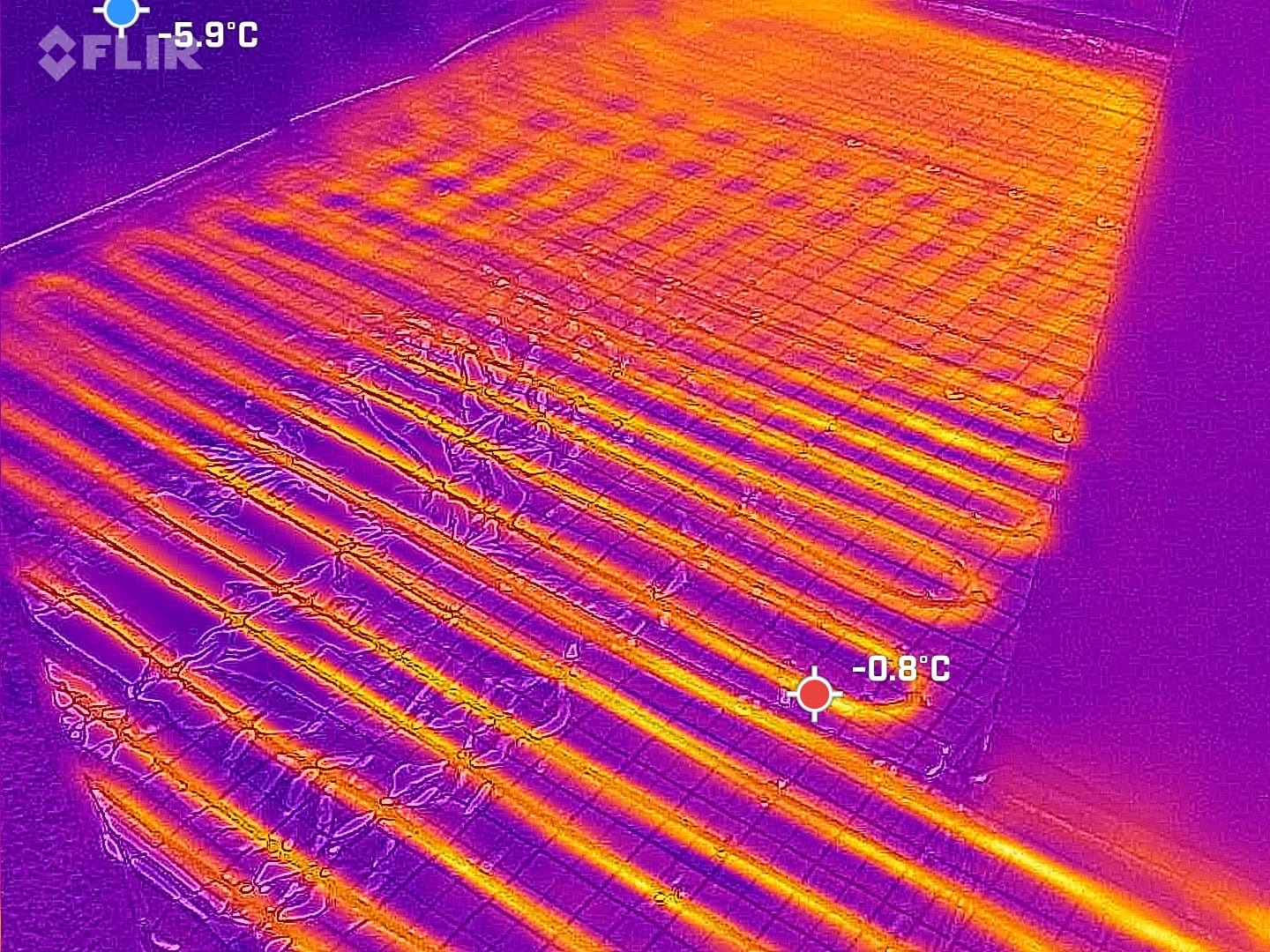Termowizyjne zdjęcie ogrzewania podłogowego w trakcie pracy, ukazujące rozkład temperatur. Widoczne rury grzewcze w odcieniach pomarańczy i fioletu.