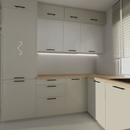 Stolarnia Gwiaździsta Grzegorz Kazanowski - Jasna kuchnia z drewnianym blatem, czarną armaturą i minimalistycznymi uchwytami. Nad blatem górne szafki z oświetleniem LED. Obok drzwi wejściowe.