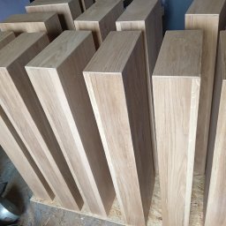Stolarnia Gwiaździsta Grzegorz Kazanowski - Drewniane, jasne kantówki ułożone pionowo na płycie OSB. Widoczne słoje drewna i precyzyjne wykończenie. Elementy do konstrukcji meblowej lub schodów.