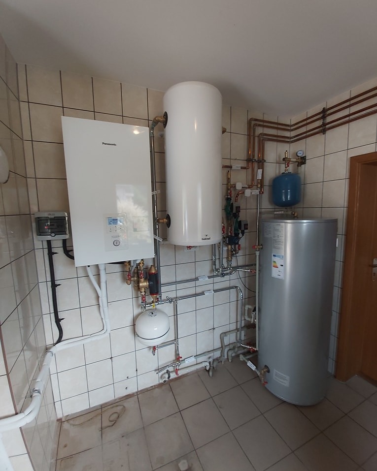 Kompleksowa instalacja grzewcza w kotłowni: piec gazowy Panasonic, zasobnik ciepłej wody, naczynie przeponowe i miedziane rury. Wykończenie w płytkach.