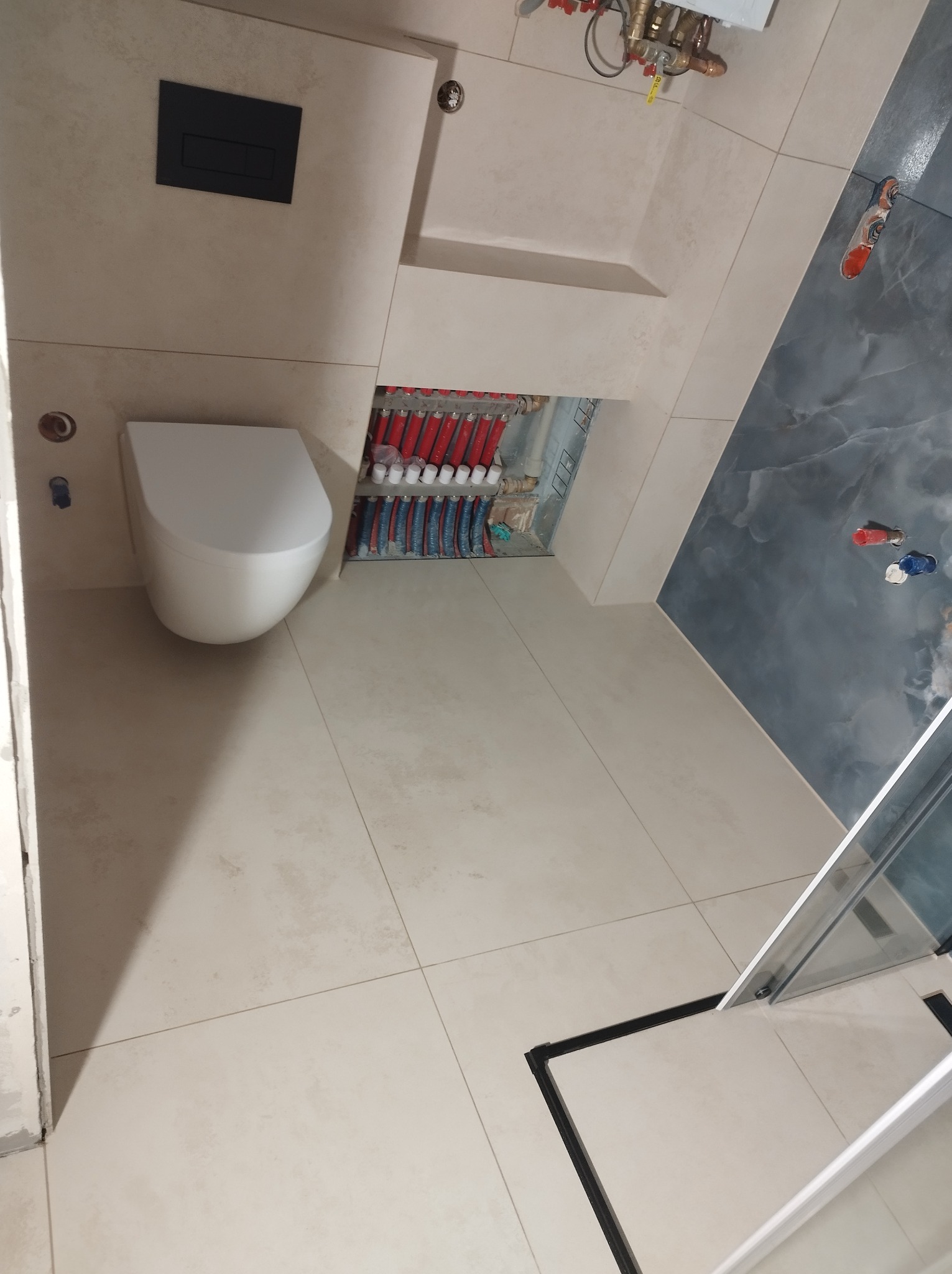 Nowoczesna łazienka z podwieszaną toaletą i marmurową ścianą w Chrzanowie. Widoczne ogrzewanie podłogowe i minimalistyczny design.