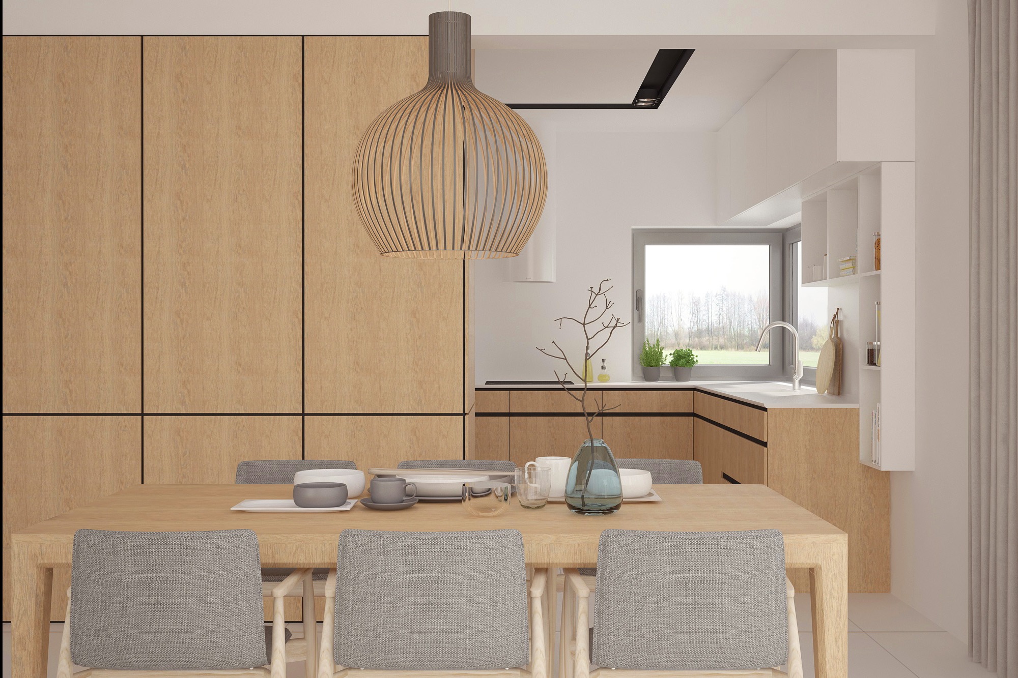 Jasna kuchnia z drewnianymi frontami, stół z szarymi krzesłami i dekoracyjna lampa wisząca. Minimalistyczny design z akcentami naturalnego drewna i roślin.