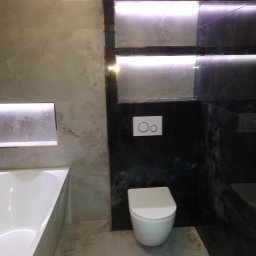 Michał Waszak - Nowoczesna łazienka z marmurowymi płytkami, podświetlanymi niszami i wiszącą toaletą. Minimalistyczny design z akcentami światła.