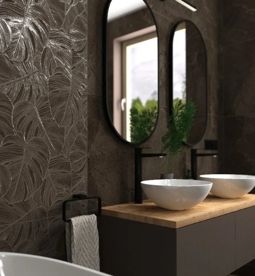 Nowoczesna łazienka z ciemnymi płytkami w liście, owalnymi lustrami i białymi umywalkami nablatowymi. Minimalistyczny design z akcentami roślinnymi.