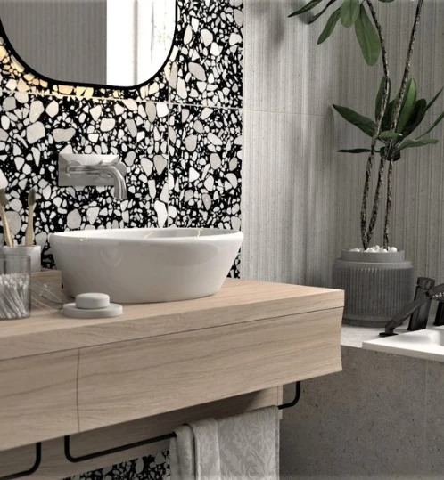 Nowoczesna łazienka w Zduńskiej Woli: biała umywalka nablatowa, bateria, lustro w czarnej ramie i ściana z mozaiką lastryko. Minimalistyczny design z rośliną doniczkową.