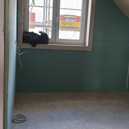 Atom - Poddasze w trakcie wykańczania: ściany z płyt karton-gips, drewniane okno z widokiem na rusztowanie, drewniana boazeria na skosie dachu, kable elektryczne.