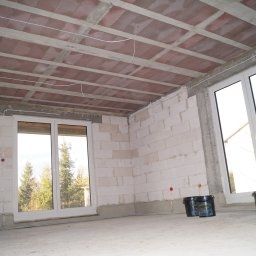 DREBEKO - Surowy stan wnętrza z oknami i stropem Teriva w Mińsku Mazowieckim. Widoczne puszki z farbą, ściany z bloczków i instalacje elektryczne.